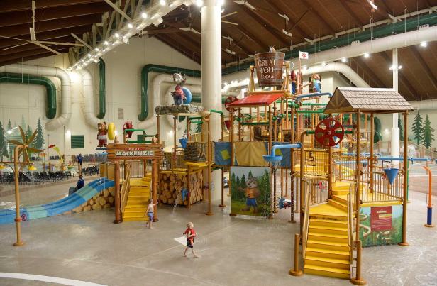 A towering complex of water features, wtih yellow stairs, blue slides, brown climbing bars and more.