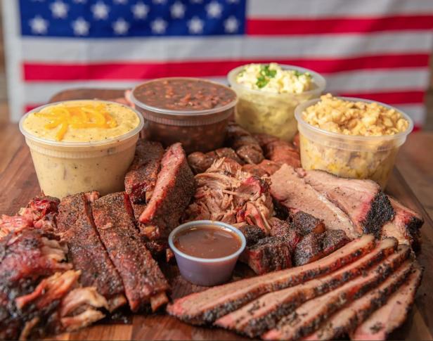A selection of barbecue meats and sides with an American flag in the background