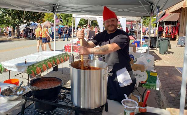 Man stirring a large pot of chili at a cook-off