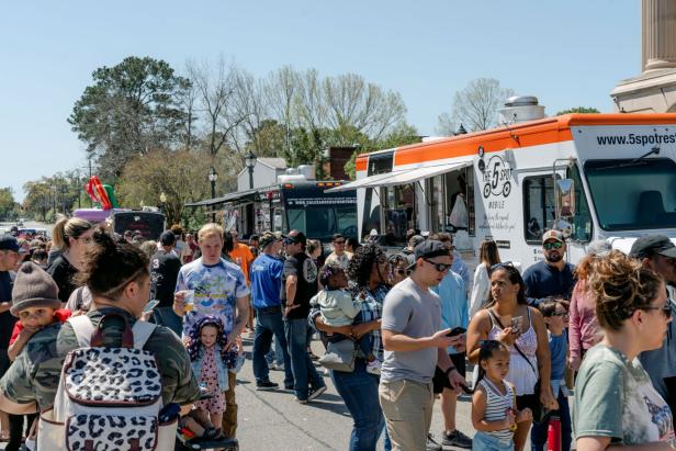 People enjoying a food truck festival on a sunny day