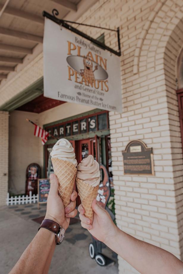 Ice cream cones held up in front of an ice cream shop.