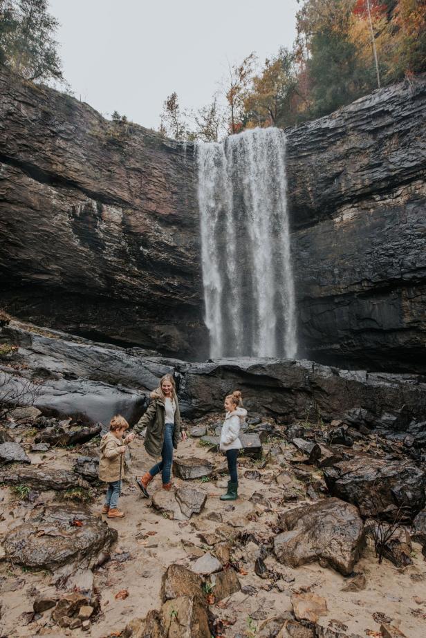 Family walking on rocks at the base of a waterfall