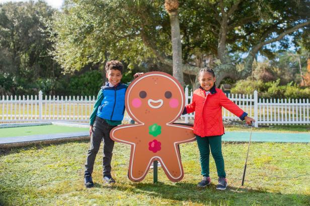 Two kids outside standing next to a large gingerbread cutout in the yard in Georgia