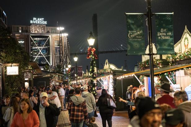 Holiday shoppers at a Christmas market at night