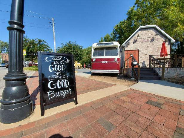 Exterior of the Ball Ground Burger Bus with a sign on the sidewalk that reads "Today is a good day to have a good burger"