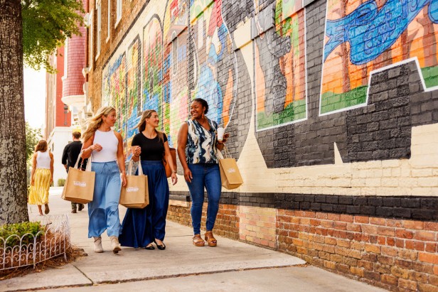Group of girlfriends with shopping bags, smiling and looking at each other.