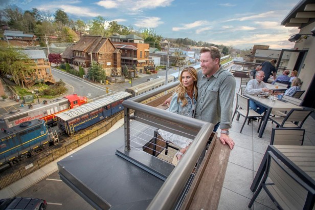 A couple standing by an edge of an elevated patio looking out into the downtown view.