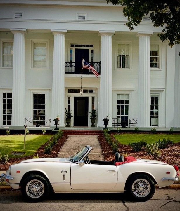 White convertible car parked in front of the white-columned The Athenian in Athens, Georgia