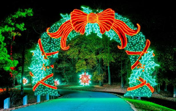 A giant arch of lights in the shape of a Christmas wreath arcs over a road at Fantasy in Lights in Pine Mountain, Georgia