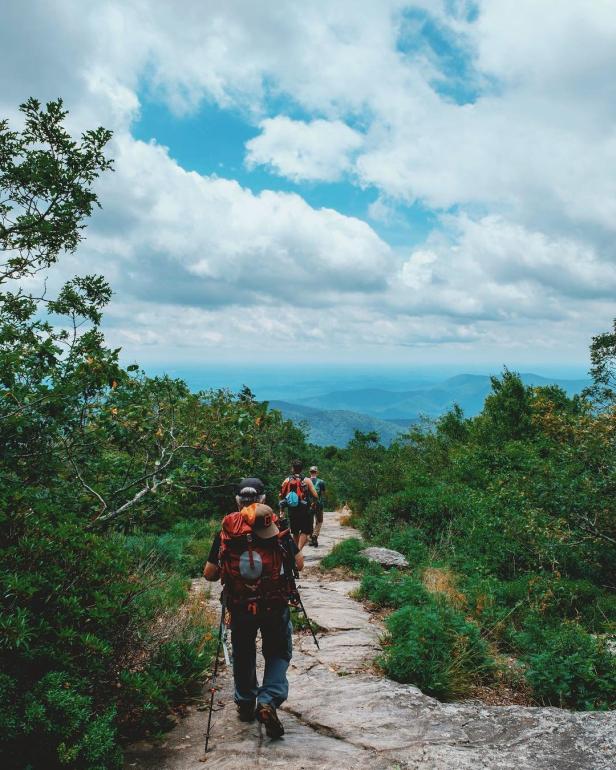 Hikers walk along a trail in the mountains.