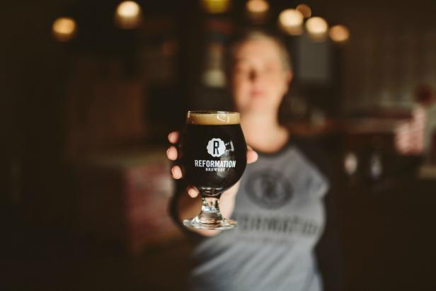 Woman holding a beer at Reformation Brewery in Woodstock, Georgia