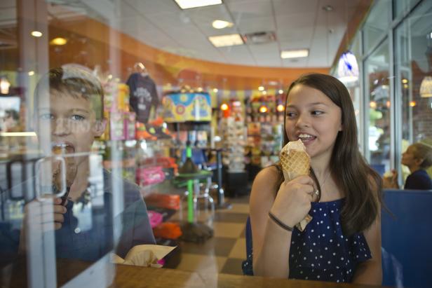 Children eating ice cream inside an ice cream shop.