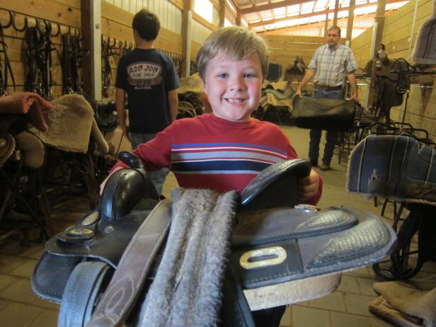 Boy holding a saddle at Southern Cross Guest Ranch in Madison, Georgia