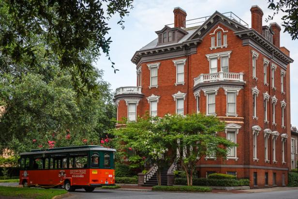A trolley drives by the red-brick Kehoe House