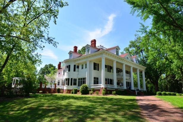 Exterior of a large white bed and breakfast framed by trees.