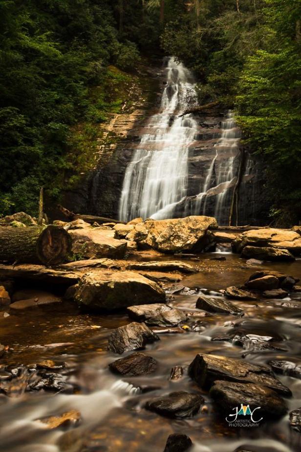 A waterfall flows down into a rocky riverbed.