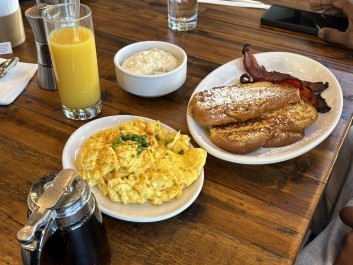 A breakfast spread with fluffy scrambled eggs, french toast, bacon, fresh orange juice, and creamy oatmeal at Love You Brunches in Conyers.