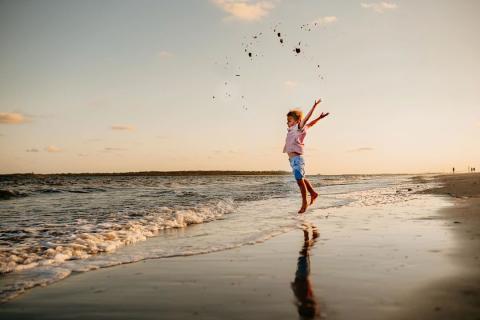 Child jumping on beach at St. Simons Island, Georgia. Photo by @bowtiesandbloomphotography