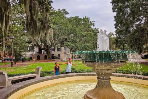 Two kids outside near a fountain at Telfair Square in Savannah, Georgia. Photo by @2traveldads