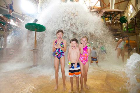 Three children laugh while getting sprayed with water at Great Wolf Lodge