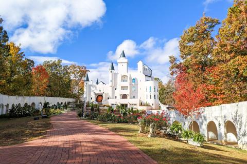 A white castle is surrounded by colorful fall foliage in the mountains