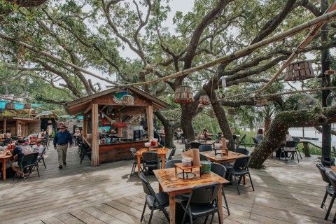 A large outdoor dining deck surrounded by large trees