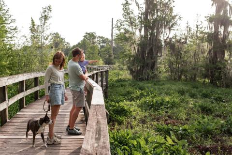 Family and a dog on a boardwalk in Phinizy Swamp Nature Park in Augusta, Georgia