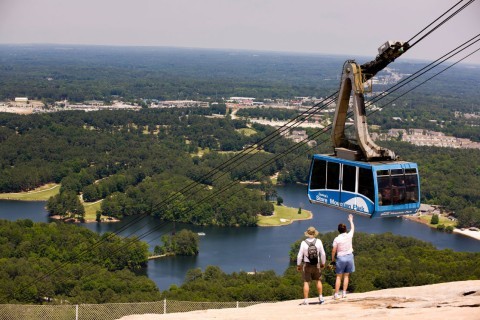 Couple on top of Stone Mountain waving at the cable car