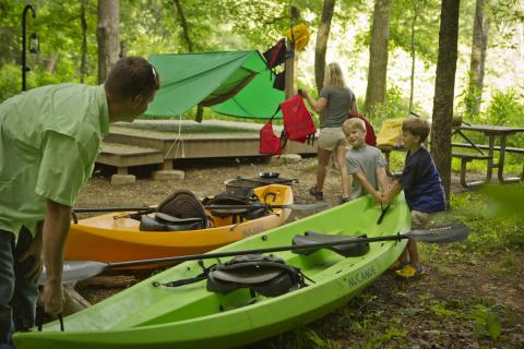 Kids carry a kayak in a campground