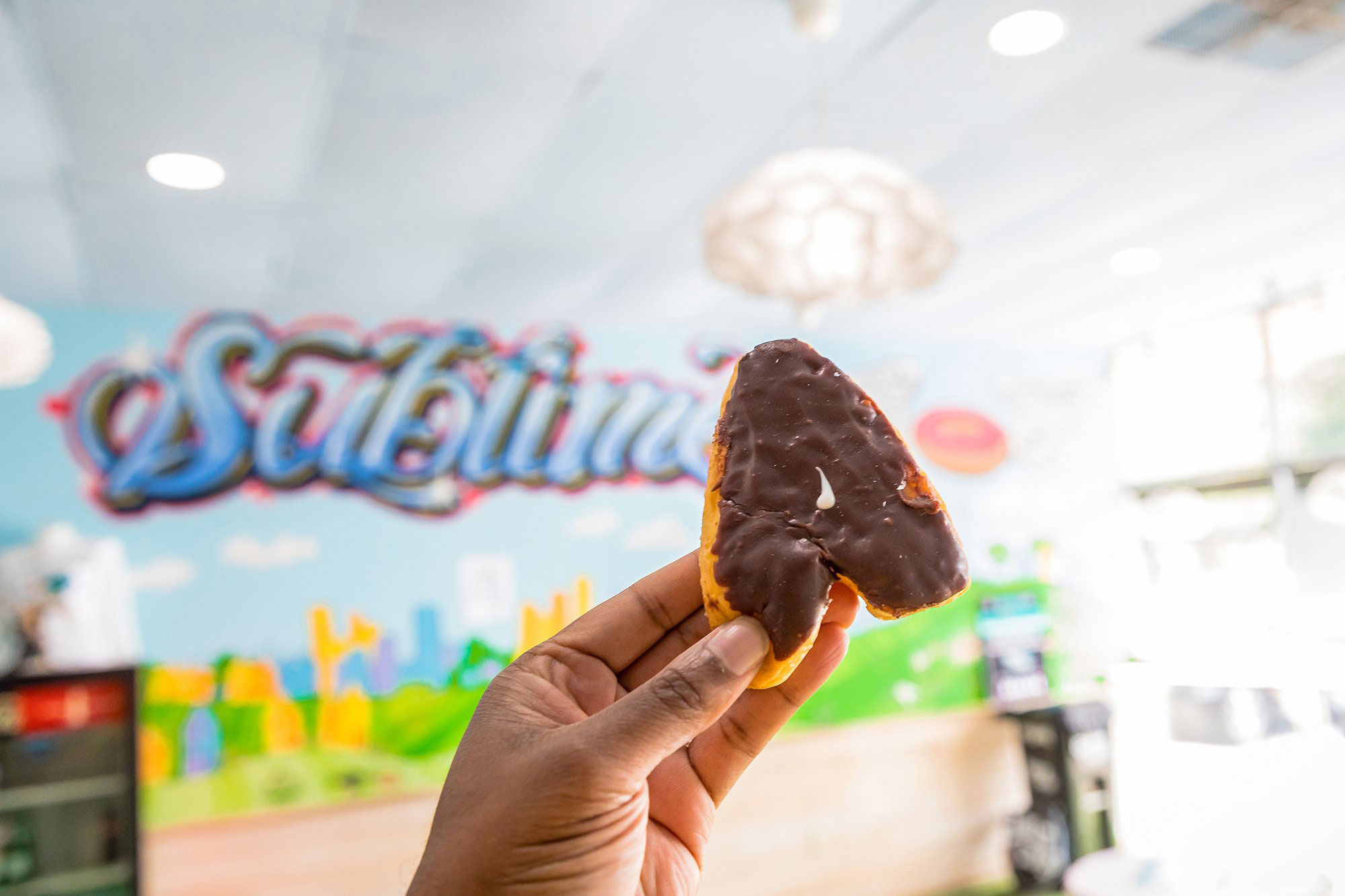 Hand holding an A-shaped doughnut at Sublime Doughnuts in Atlanta, Georgia