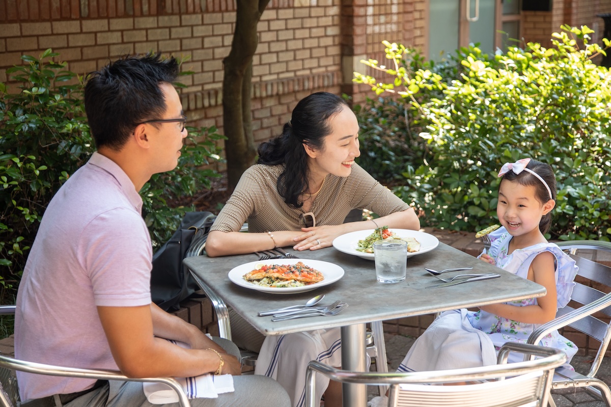 Family of three sitting at table, parents looking at daughter, at Mare Sol