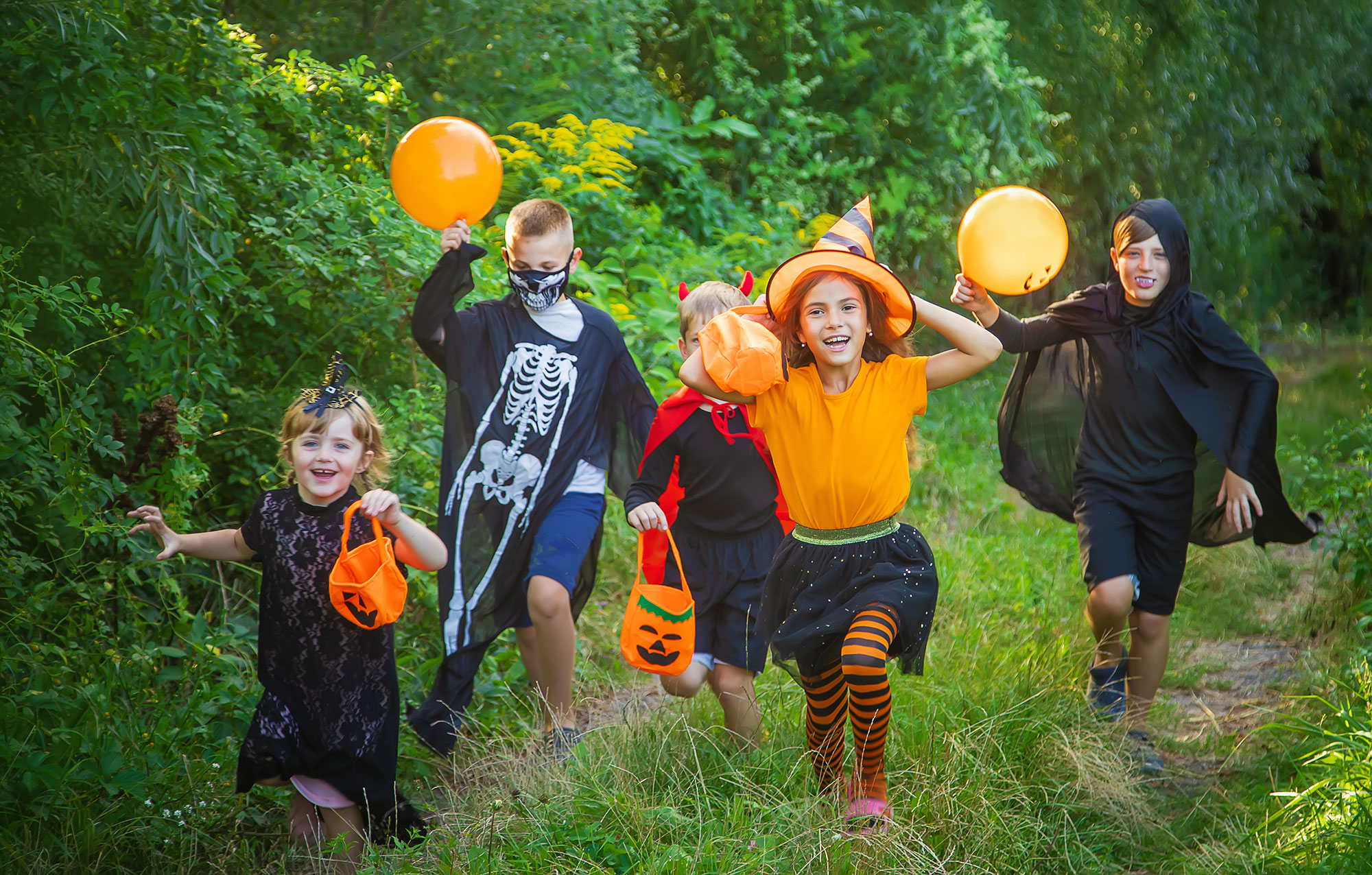 children dressed in Halloween costumes walking along a wooded a trail