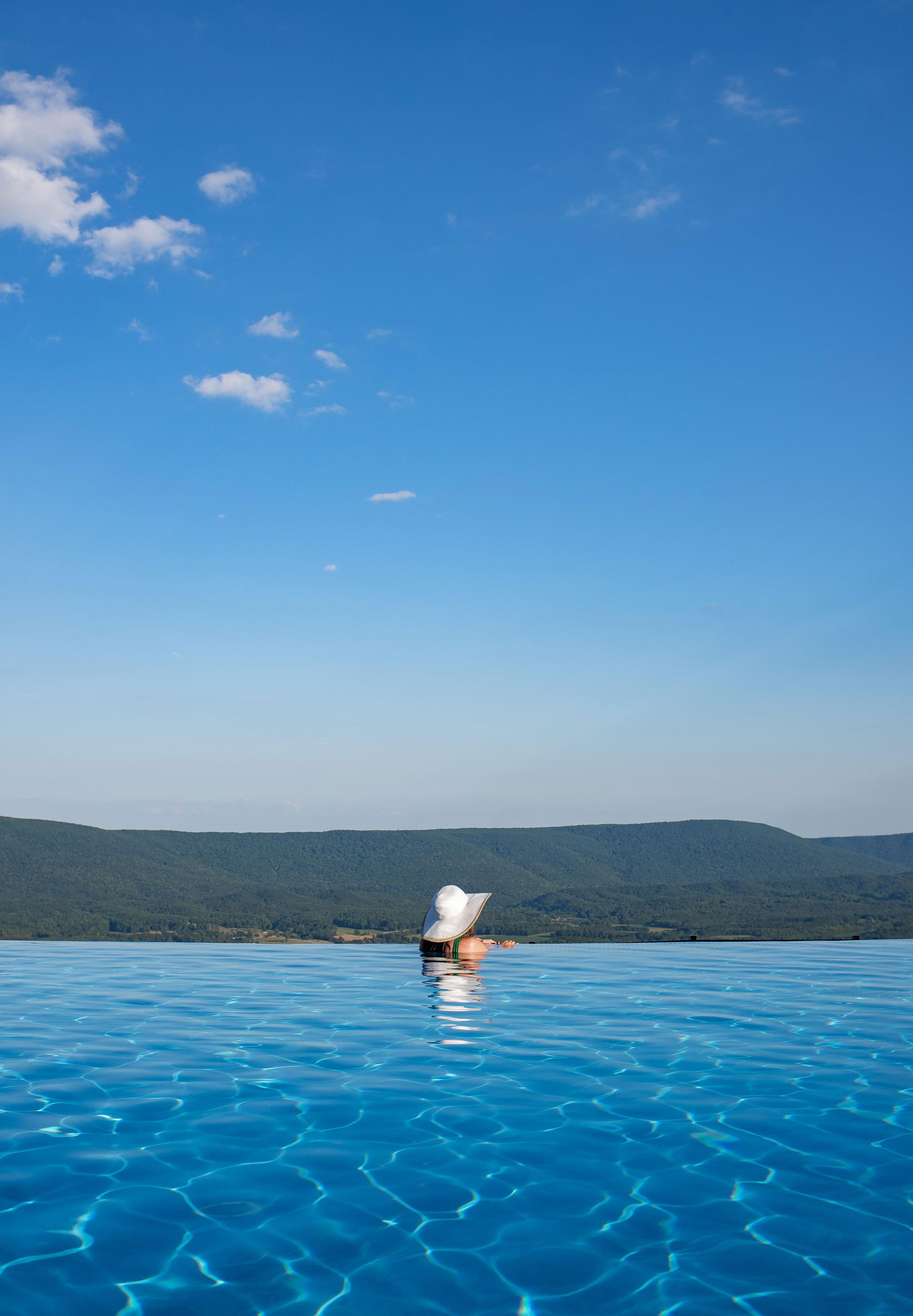 Woman gazing past the edge of an infinity pool at Cloudland at McLemore Resort in Lookout Mountain, Georgia